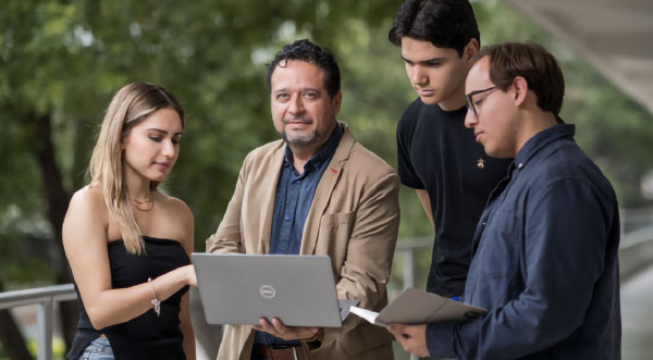 Profesor del Tec de Monterrey asesorando a estudiantes en proyecto académico con enfoque en liderazgo y transformación
